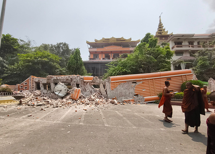 Buddhist monks walking past a collapsed building in Myanmar after an earthquake.