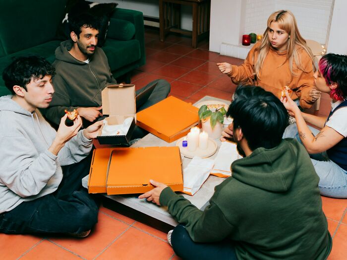 Group of friends enjoying pizza, representing 'lifetime supply' winners sharing their experiences in a cozy setting.