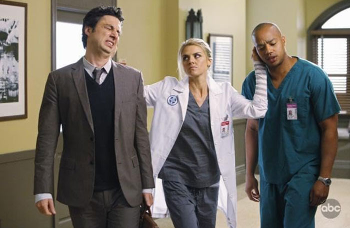 Actors from 'Scrubs' in a hospital scene, featuring a doctor and nurse interacting with a man in a suit.