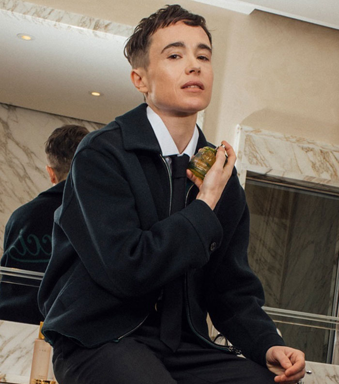 Transgender actor in a stylish setting, wearing a dark jacket and holding a small golden object, promoting movie industry transformation.