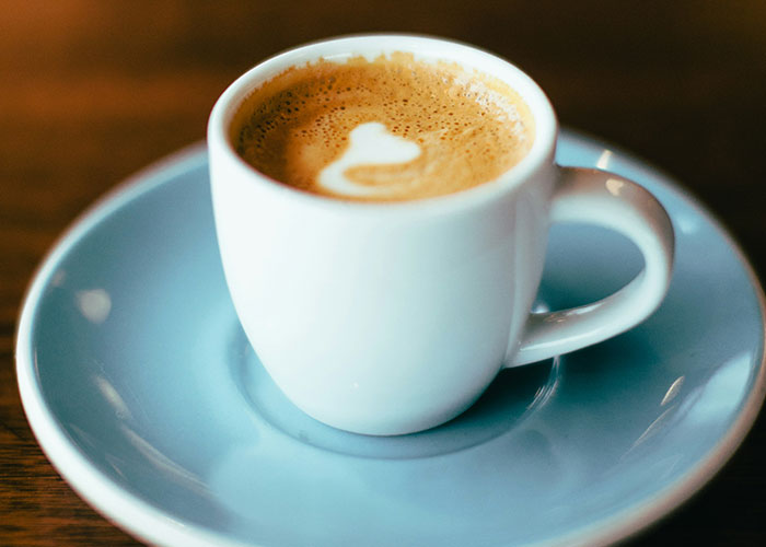 A cup of coffee with heart foam art, highlighting a restaurant setting.