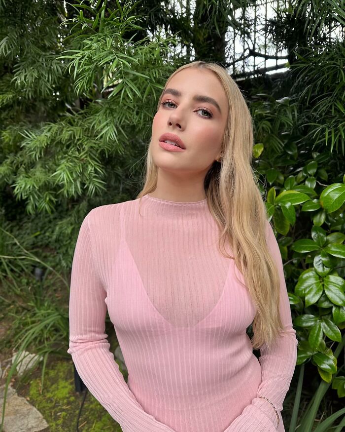 A woman in a pink top stands outdoors with lush greenery, embodying the theme of not-self-made-celebs.
