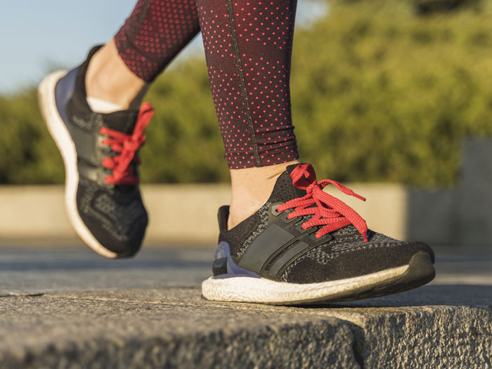 Woman in sports trainers with red laces, walking on a stone path, wearing polka dot leggings. Woman in sports trainers with red laces, walking on a stone path, wearing polka dot leggings.