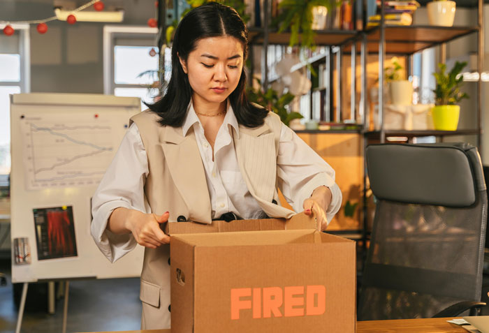 Woman in office packing belongings after workplace mistreatment lawsuit success over wearing trainers. Woman in office packing belongings after workplace mistreatment lawsuit success over wearing trainers.