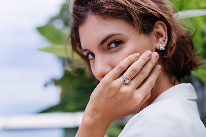 Woman displaying a ring, covering her mouth with a hand, symbolizing a reaction to a swapped ring story.
