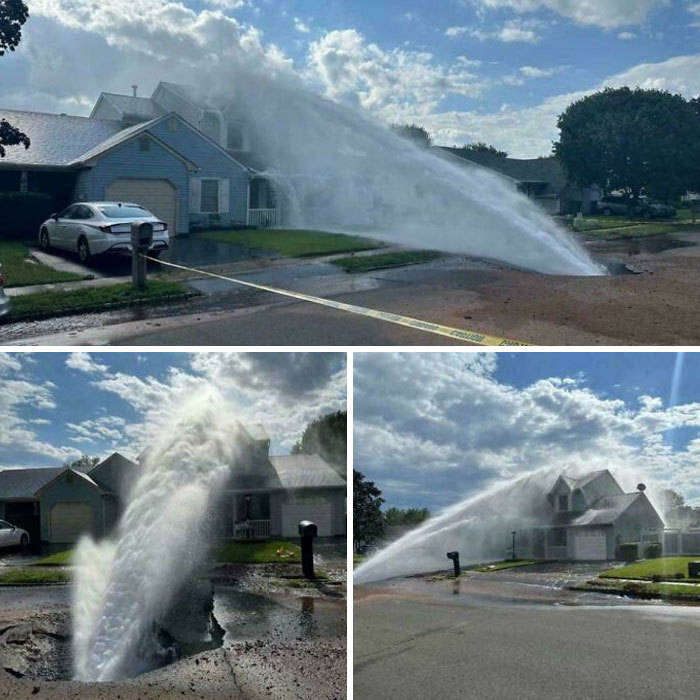 Water geyser from a street accident flooding a suburban neighborhood road under a clear sky.