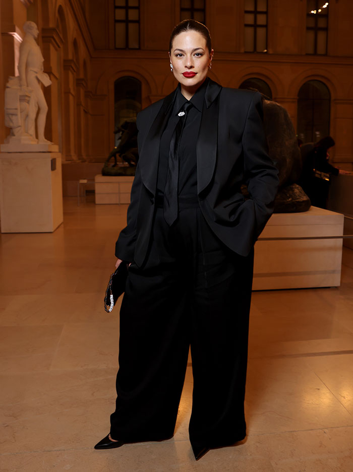 Celebrity woman in a stylish black suit posing at an elegant event, showcasing fashion and confidence.