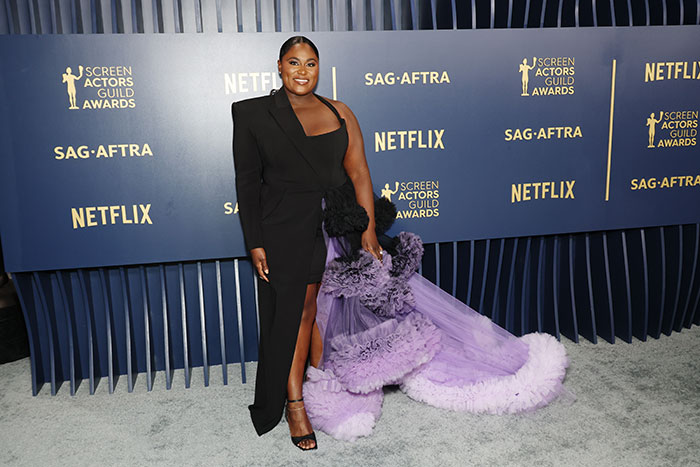A celebrity woman in a chic black and purple gown at an awards event, highlighting celebrity designers.