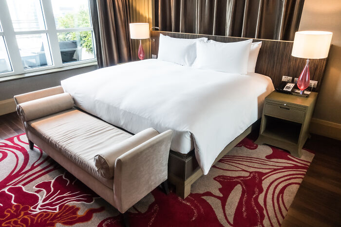 Luxurious bedroom with a large bed, elegant bench, and stylish lamps, creating an impactful and inviting space.