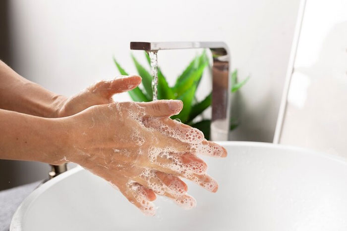 Close-up of hands lathered with soap under running water, emphasizing cleanliness and hygiene.