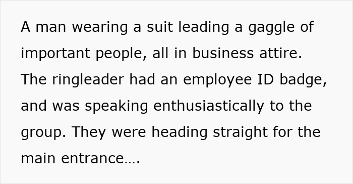 A suited man leads businesspeople, ID badge visible, speaking with enthusiasm toward a main entrance.