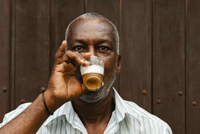 Man drinking coffee, wearing a striped shirt, symbolizing reasons friends drift apart.