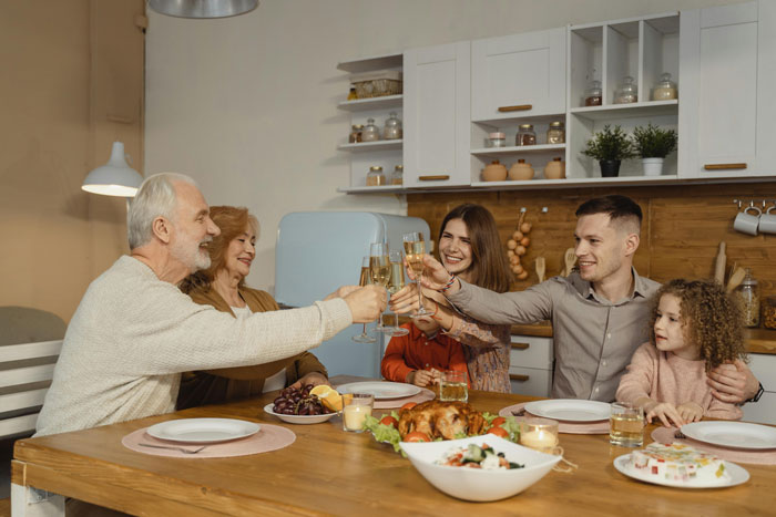 Family celebrating with a toast at a festive dinner table, highlighting community respect.