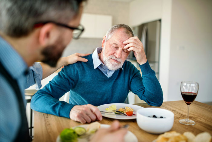 Man in a kitchen looking distressed, receiving comfort; a conversation about respect in the community occurs.