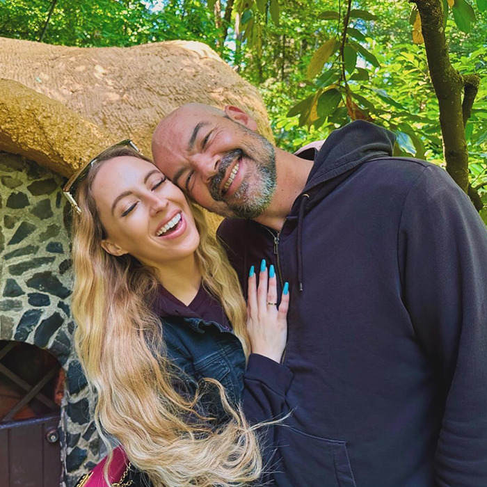 TV star's wife smiling with husband outdoors, sinister intent concept.