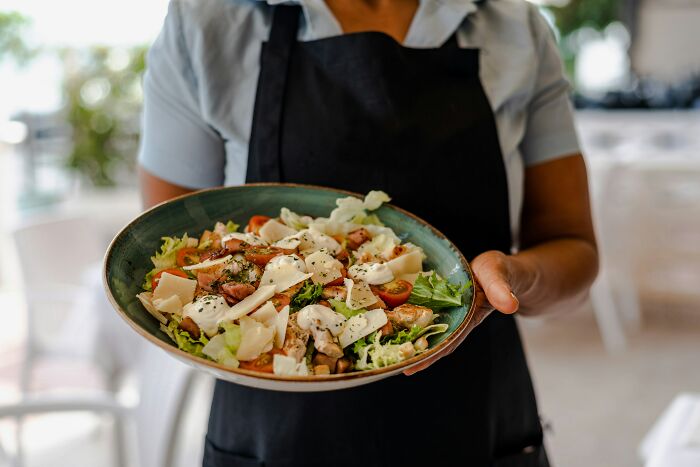 Person holding a salad with greens, tomatoes, and cheese, representing misunderstood healthy foods.
