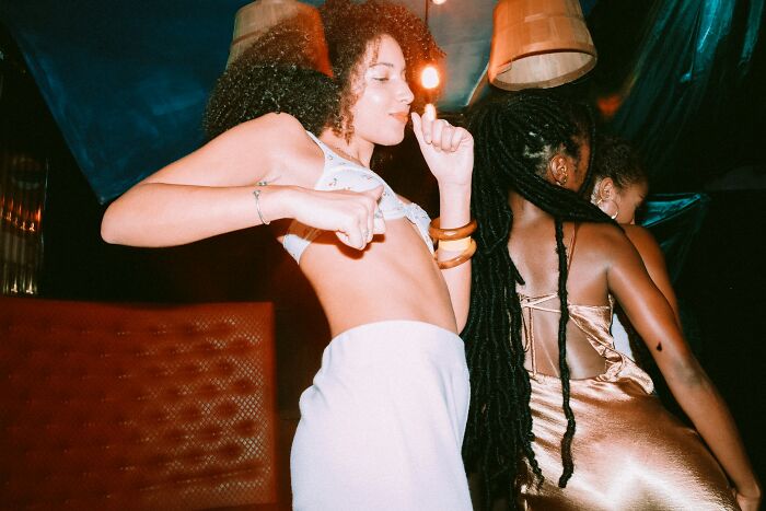 Two women dancing energetically in a dimly lit room, capturing a secretive nightlife vibe.