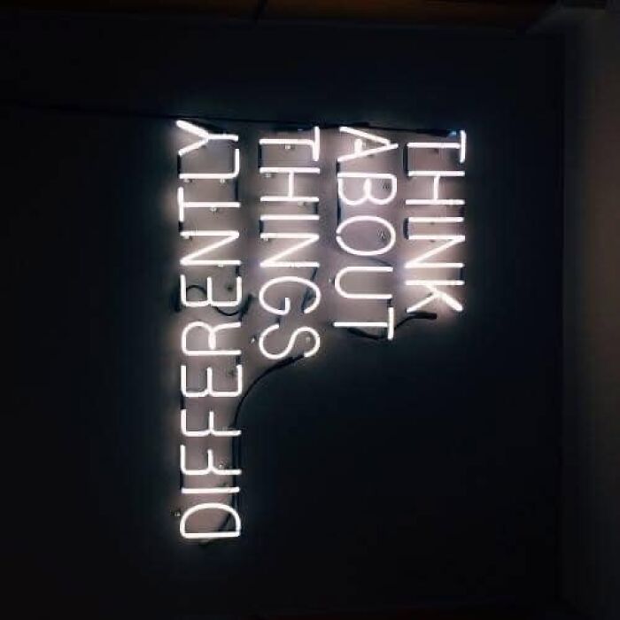 Neon sign with "Think About Things Differently" promoting mental health awareness.