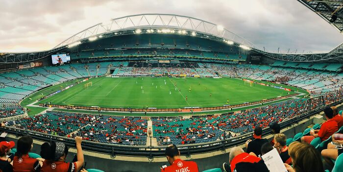 Panoramic view of a large soccer stadium filled with fans watching a live match in historic cathedrals of soccer.
