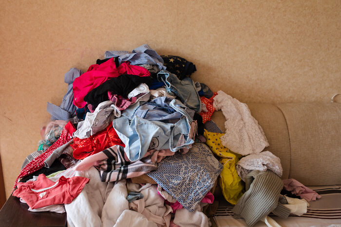 Pile of clothes on a sofa, depicting clutter in homes often accepted as normal by society.