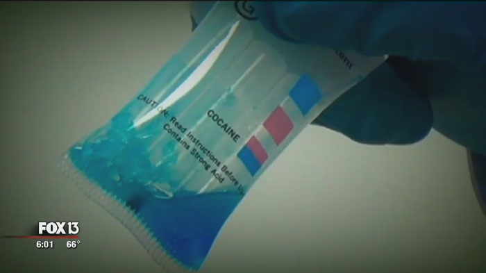 Gloved hand holding a c*****e test kit, as shown on FOX 13 news.