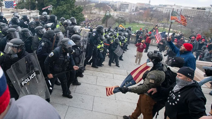 Police confront protesters on Capitol steps, highlighting a chaotic scene.