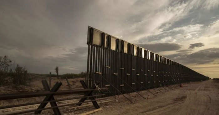 Desolate landscape view of a long border fence under a cloudy sky, illustrating a concept related to Florida Man headlines.
