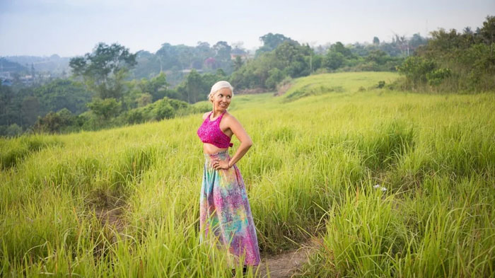 Woman in colorful attire standing in a grassy field under a cloudy sky, embodying Florida Man vibe.