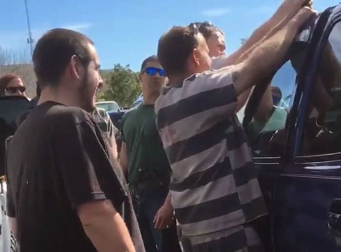 Group of men, one in striped clothing, working to open a car door, depicting a scene typical of Florida Man headlines.