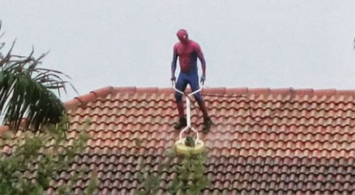Florida Man in a Spider-Man costume pressure-washes a roof.
