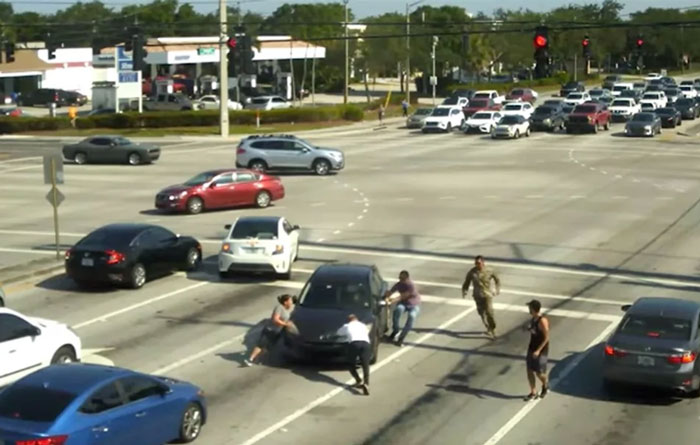 People stopping a car at a busy Florida intersection, showcasing a chaotic scene from a 'Florida Man' event.