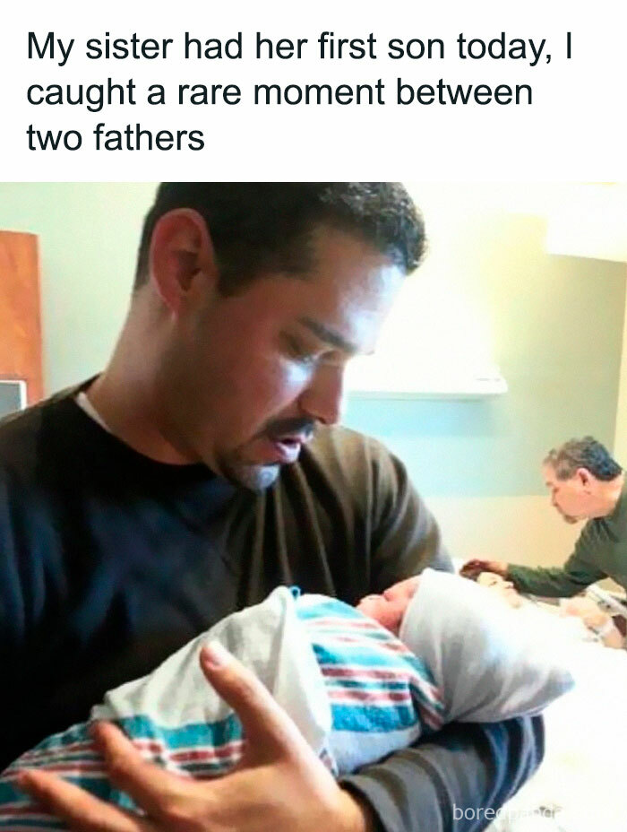 Man holding a newborn, with another man doting in the background, creating a sarcastic family scene.