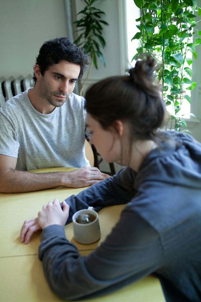 Man and woman sitting at a table, engaged in a serious conversation, relating to moments of rejection.