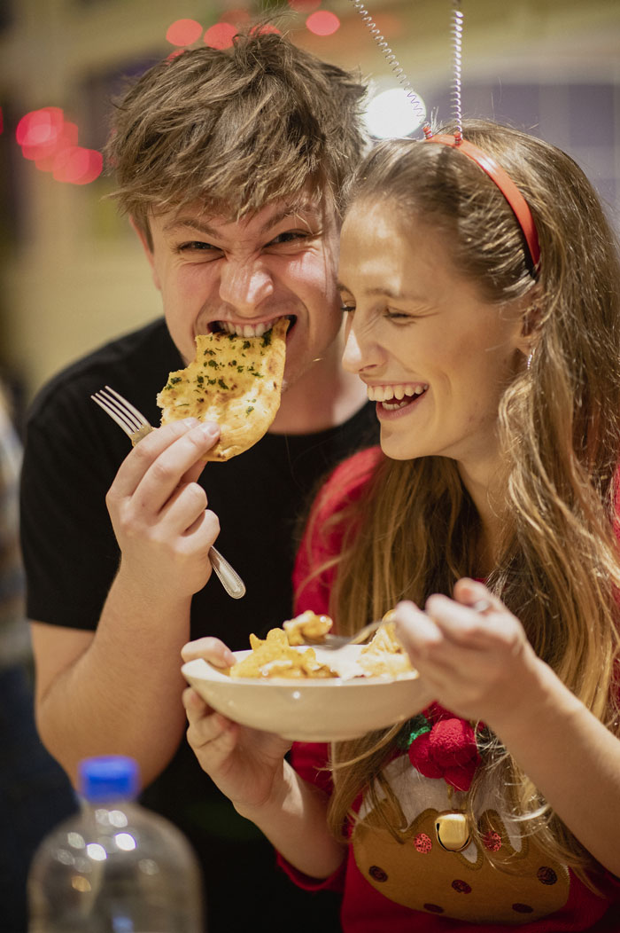 Two people eating and laughing, capturing a fun moment of Gen Alpha's lively social life.