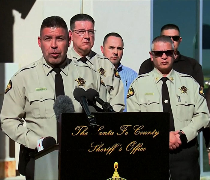 Sheriff's department at a press conference, discussing medical examiner's broken heart theory.