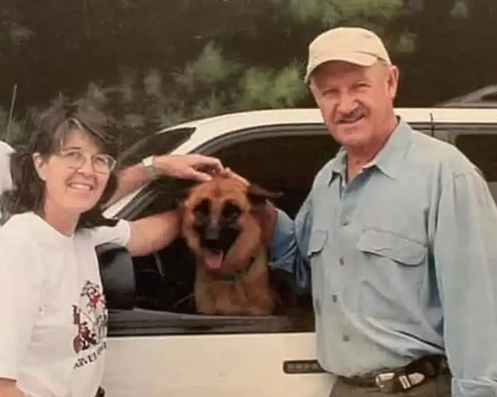 Gene Hackman smiling with a dog in a car.