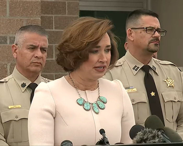 A woman speaks at a press conference, flanked by two officers, regarding Gene Hackman&rsquo;s family's actions.