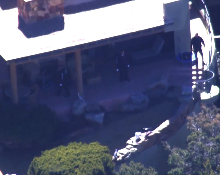 Aerial view of a house terrace with investigative personnel, related to a medical examiner's theory on broken heart-type conditions.