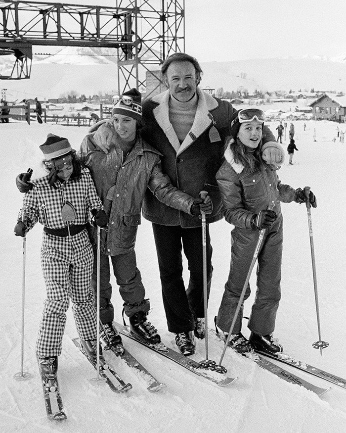 Gene Hackman smiling with kids on snowy slopes.