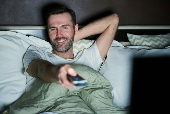 Man relaxing in bed with remote, depicting reasons friendships with besties can change.