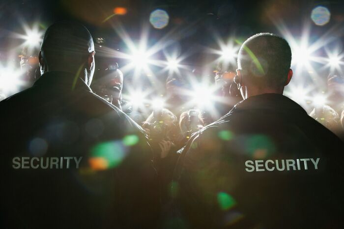 Security guards facing a crowd with flashing lights, highlighting the concept of an eating competition for easy money.