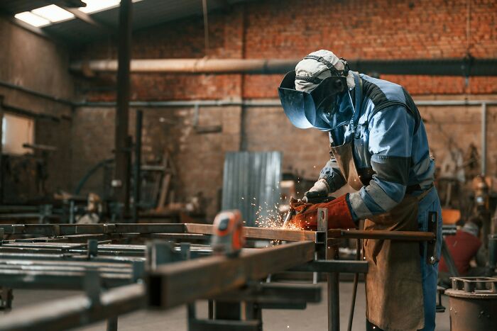 A worker in safety gear welding metal in a factory, illustrating misconceptions about their job.