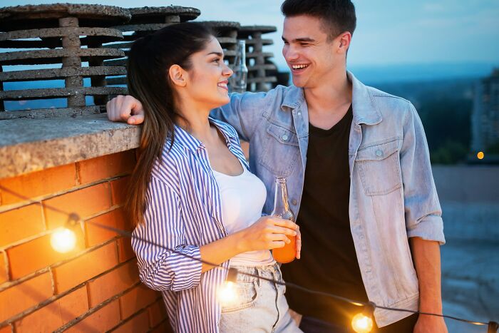 Una pareja conversando alegremente en una terraza al atardecer.