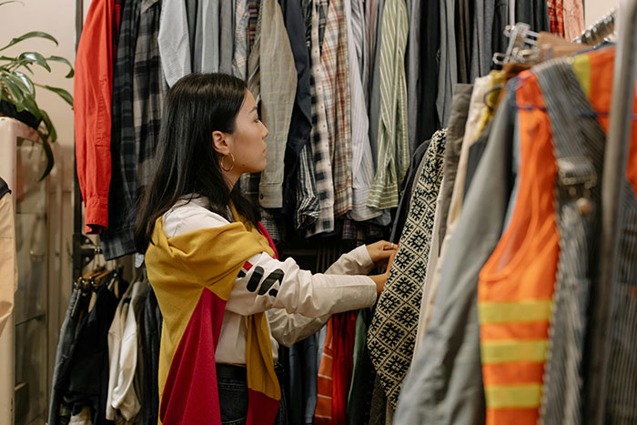 Teen girl choosing clothes in a store, wearing a colorful jacket, related to body-shaming issues.