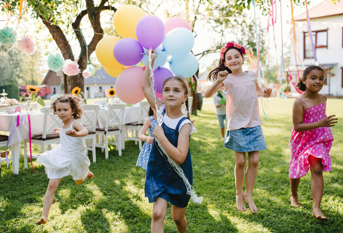 Children playing with balloons at a family gathering outdoors.