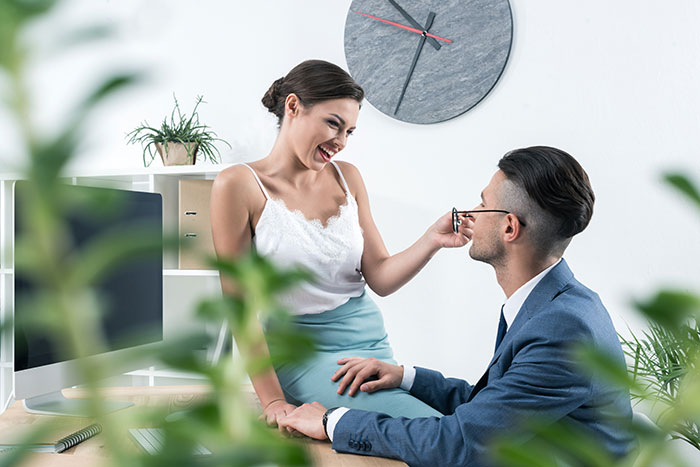 Two colleagues smiling in a modern office, symbolizing a close work relationship.