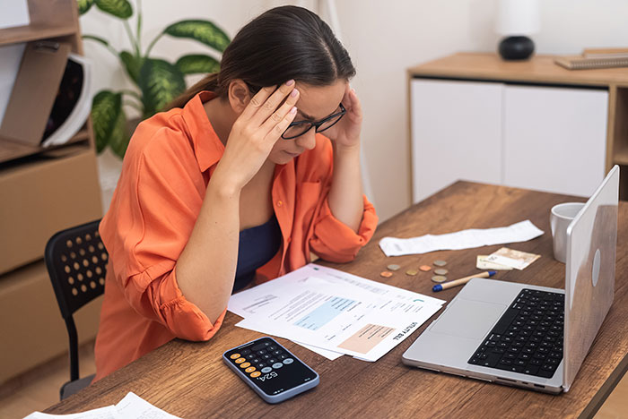 Woman stressed over bills at desk, calculating finances and expenses. Woman stressed over bills at desk, calculating finances and expenses.