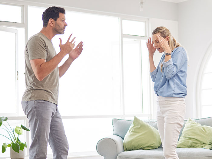 A couple arguing in a well-lit living room over a prank that went too far.