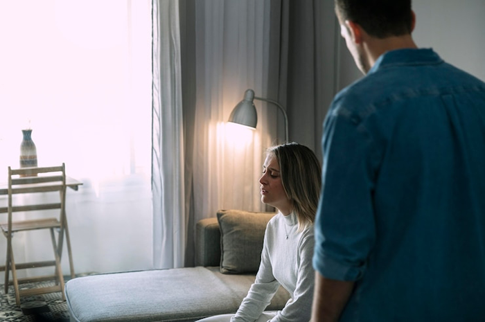 Woman looking distraught in a room with a man, dealing with attachment issues.