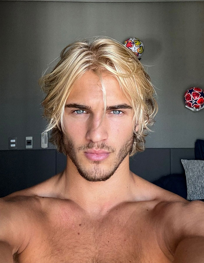 Blonde man with blue eyes, formerly "vain," transformed into a supermodel, showcasing his confident gaze.